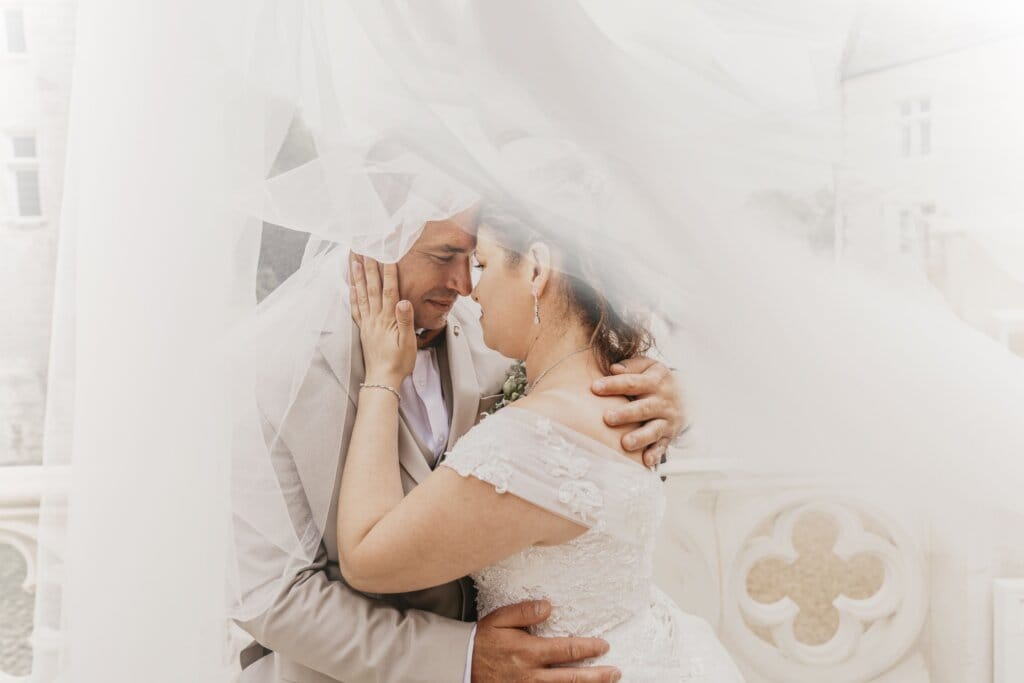 Mariés sous un voile en lumière douce, moment intime et romantique capturé lors d’un mariage en Morbihan